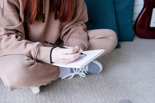 Mujer joven aprendiendo a tocar la guitarra en casa