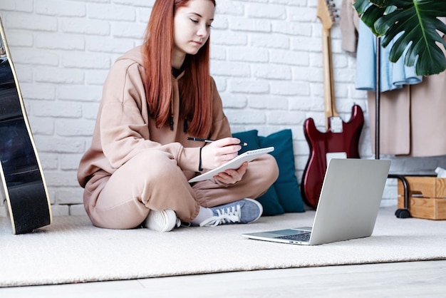 Mujer joven aprendiendo a tocar la guitarra en casa