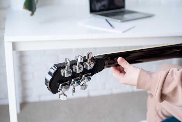 Mujer joven aprendiendo a tocar la guitarra en casa