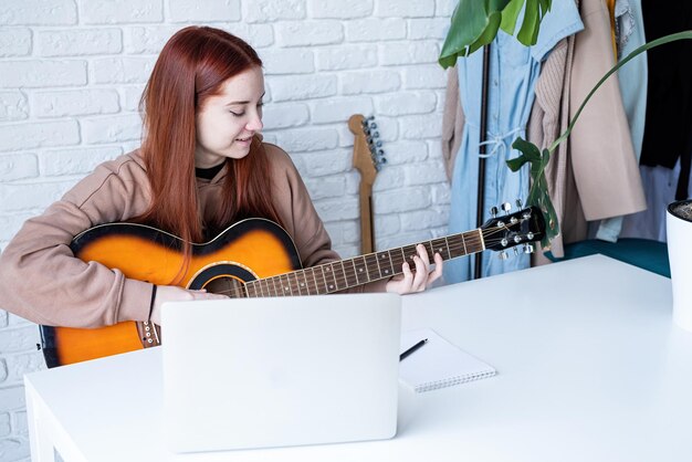 Mujer joven aprendiendo a tocar la guitarra en casa