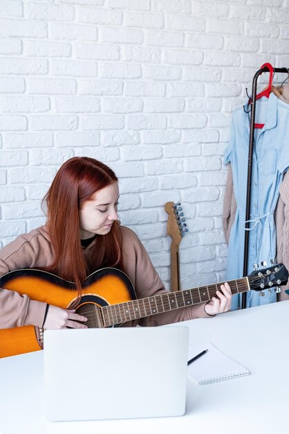 Mujer joven aprendiendo a tocar la guitarra en casa