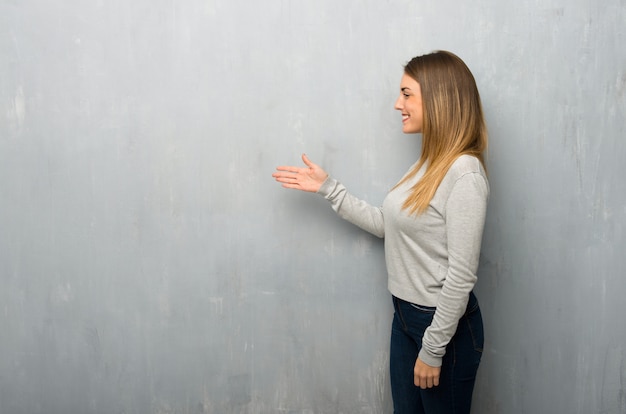 Mujer joven en apretón de manos de pared con textura después de buen trato