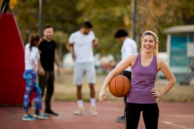 Foto mujer joven de la aptitud con la bola del baloncesto que juega al juego al aire libre