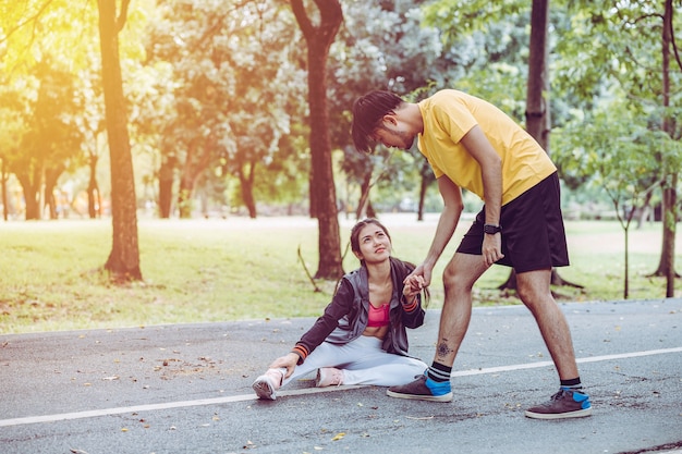 Foto la mujer joven de la aptitud que se sostiene el tobillo con dolor, hombre está ayudando, lesión del deporte.