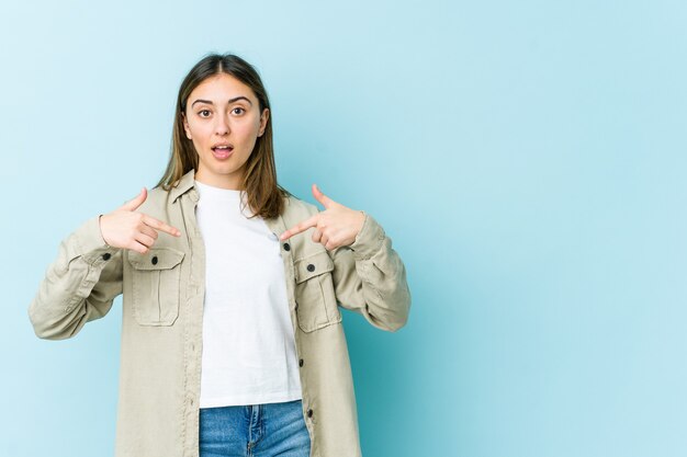 Mujer joven apunta hacia abajo con los dedos, sentimiento positivo