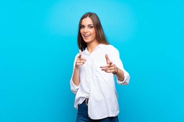 Mujer joven apuntando al frente y sonriendo