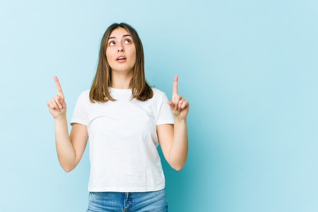 Mujer joven apuntando al revés con la boca abierta