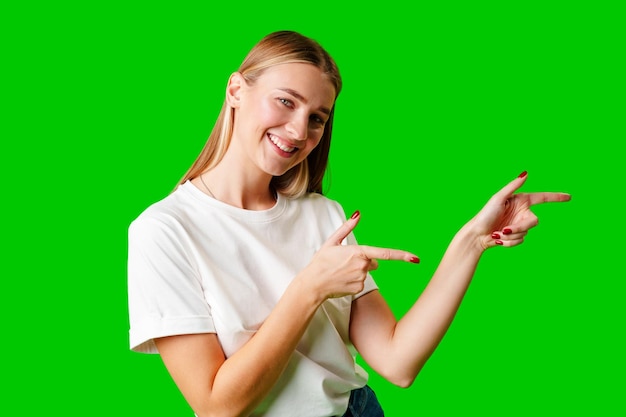 Mujer joven apuntando a algo contra un fondo verde