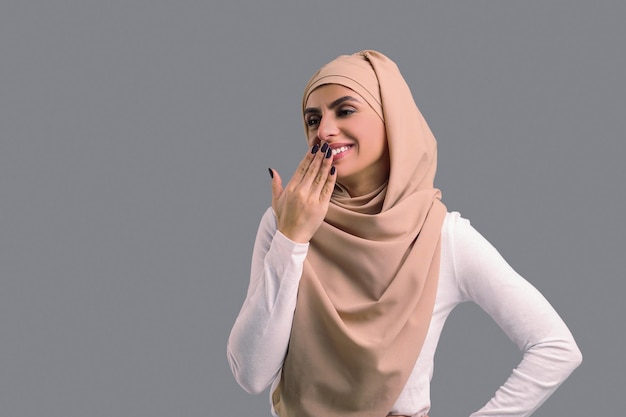 Foto mujer joven árabe en hiyab beige que parece feliz y contenta