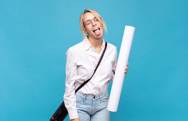 Mujer joven arquitecto con actitud alegre, despreocupada y rebelde, bromeando y sacando la lengua, divirtiéndose