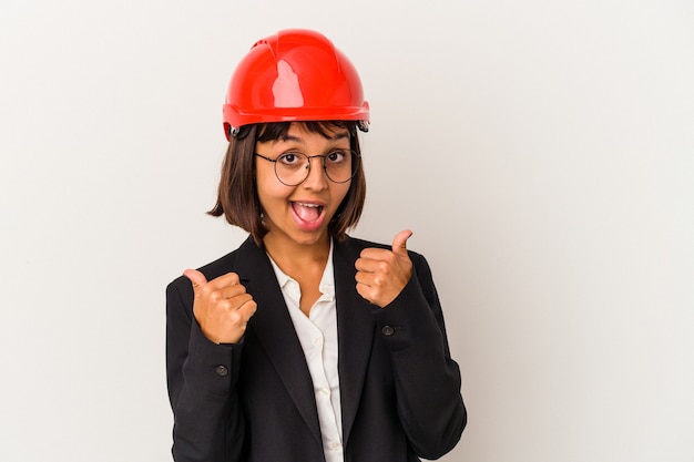 Mujer joven arquitecto con casco rojo aislado sobre fondo blanco levantando ambos pulgares, sonriente y confiado.