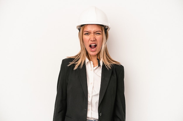 Mujer joven arquitecto caucásico con un casco aislado sobre fondo blanco gritando muy enojado y agresivo.
