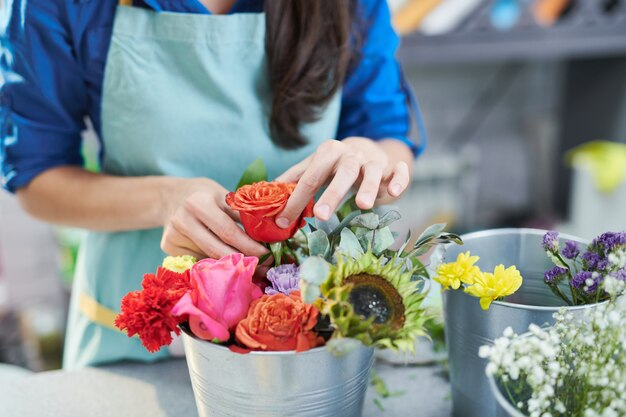 Mujer joven arreglando composición rosa