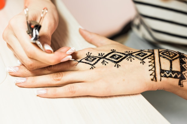 Mujer joven artista mehendi pintando henna en la mano