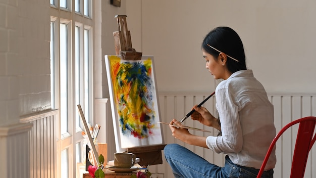 Mujer joven del artista que dibuja color de agua en el estudio.