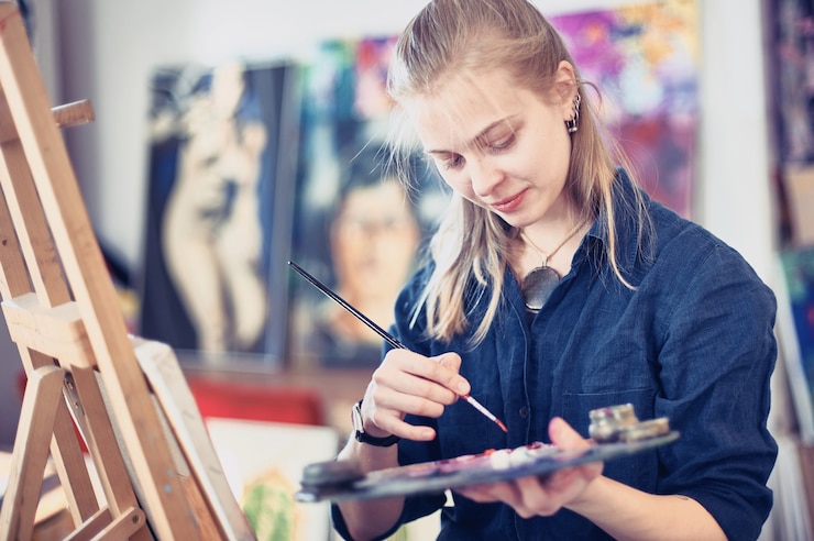 Foto mujer joven artista trabajando en pintura en estudio.