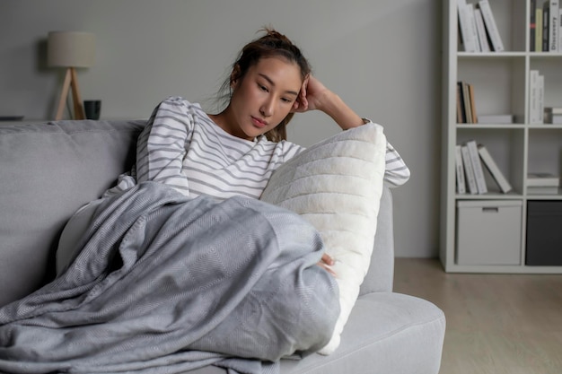 Foto mujer joven asiática acostada en el sofá en casa sintiéndose triste cansada y preocupada sufriendo depresión en salud mentalmujer padece problemas de salud mental