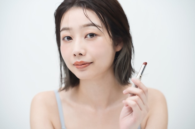 Mujer joven asiática aplicar lápiz labial en los labios