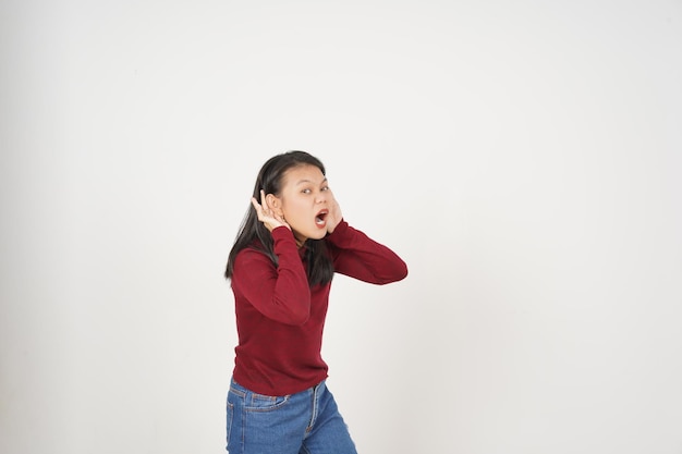 Foto mujer joven asiática en camiseta roja mano en la oreja no puede oírte concepto aislado en fondo blanco