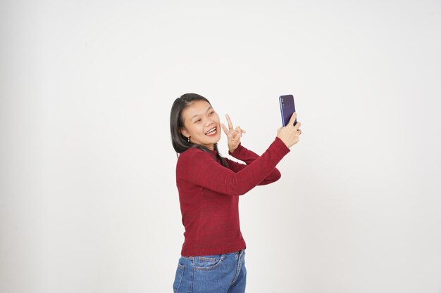 Mujer joven asiática con camiseta roja Toma una foto de Selfie aislada sobre un fondo blanco