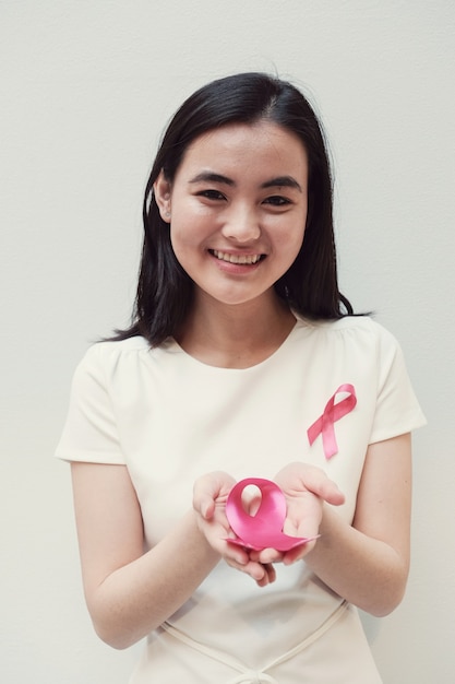 Mujer joven asiática con cinta rosa, conciencia del cáncer de mama