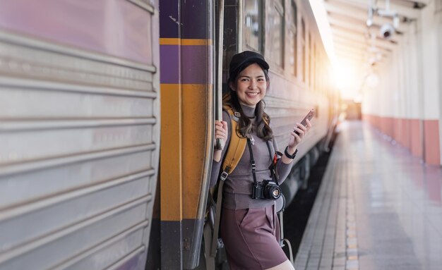 Foto mujer joven asiática en una estación de tren moderna pasajera de mochila femenina esperando el tren en el tren