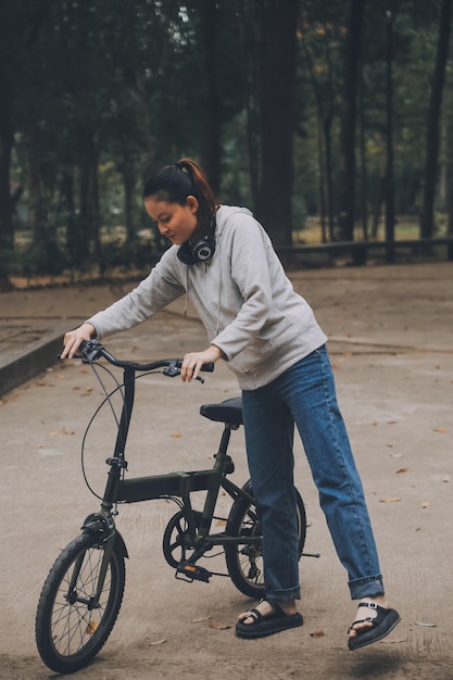 Foto mujer joven asiática feliz caminando y montando bicicleta en la calle del parque de la ciudad su sonrisa usando bicicleta de transporte ecológico amigable concepto de estilo de vida de la gente.