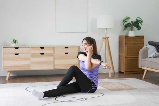 Mujer joven asiática haciendo ejercicio para estirar los brazos en el suelo para hacer ejercicio estilo de vida saludable en casa