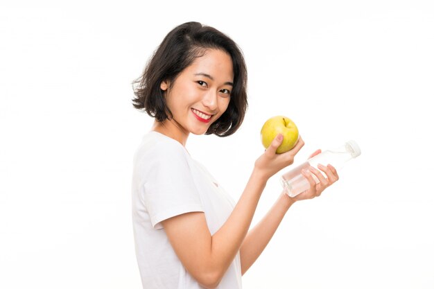 Mujer joven asiática con una manzana y una botella de agua