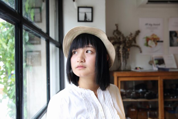 Mujer joven asiática pensando y mirando con retrato en cafetería