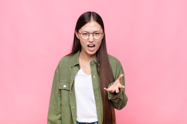 Mujer joven asiática que parece enojada, molesta y frustrada gritando