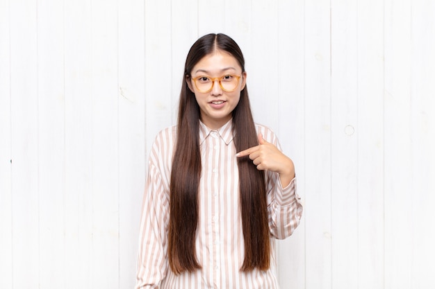 Mujer joven asiática que parece feliz, orgullosa y sorprendida