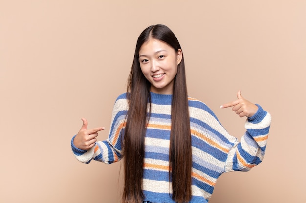 Mujer joven asiática que parece orgullosa, arrogante, feliz, sorprendida y satisfecha, apuntando a sí misma, sintiéndose como una ganadora