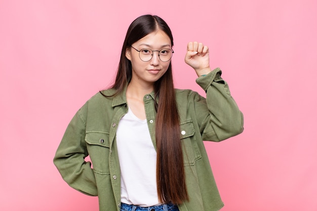 Mujer joven asiática que se siente seria, fuerte y rebelde, levantando el puño, protestando o luchando por la revolución