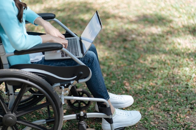 Mujer joven asiática en silla de ruedas trabajando con una computadora portátil