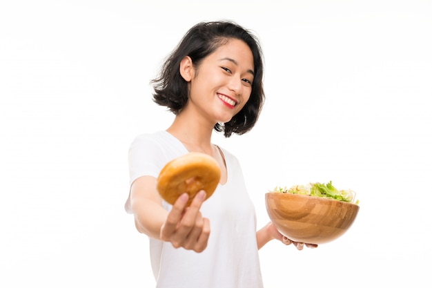 Mujer joven asiática sobre aislado con ensalada y donut