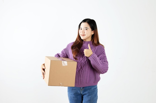 Mujer joven asiática sosteniendo una caja de paquetes con el pulgar hacia arriba