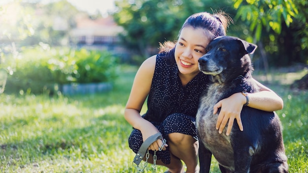 La mujer joven asiática toma el perro para caminar y jugar juntos en el jardín en casa.