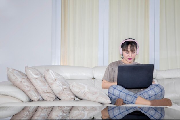 Mujer joven asiática usando una computadora portátil en el sofá