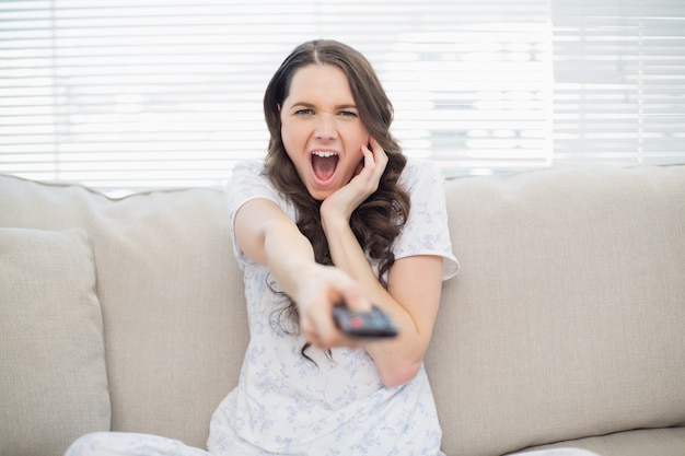 Mujer joven asustada que cambia la estación de tv