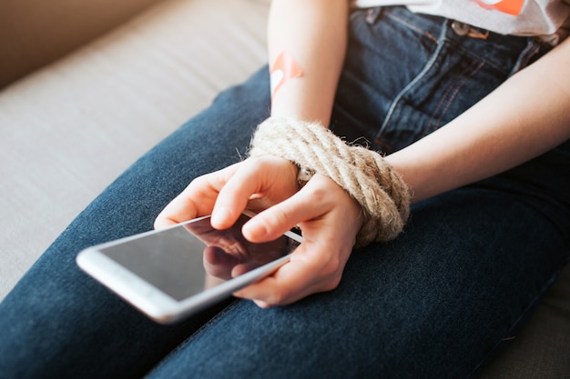 Mujer joven atada con el teléfono en sus manos