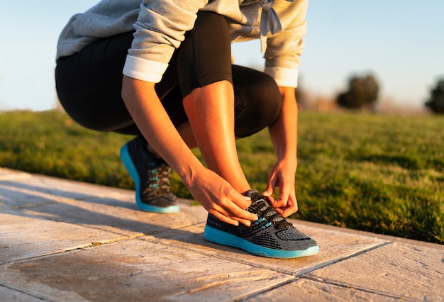 Mujer joven atar los cordones de las zapatillas de deporte para hacer correr el entrenamiento de entrenamiento. Fitness y estilo de vida saludable