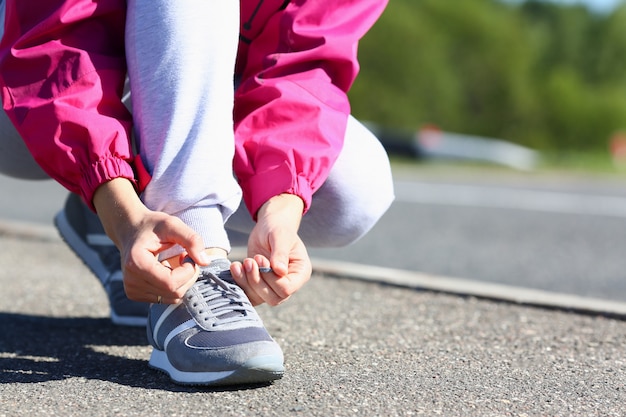 Mujer joven atar cordones de los zapatos en la calle