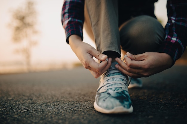 mujer joven, atarse, ella, cordones, en, ocaso