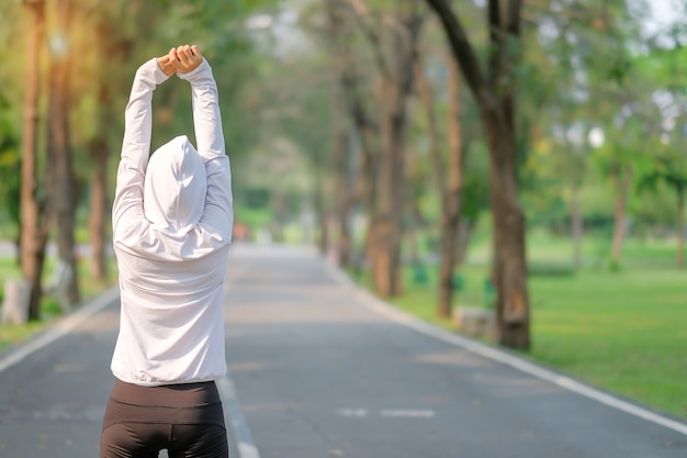 Mujer joven atleta streching en el parque al aire libre