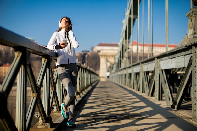 Mujer joven del atleta con el teléfono móvil al aire libre