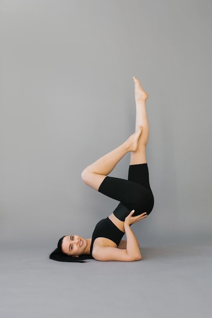 Mujer joven atlética haciendo fitness o yoga tirada en el suelo y levantando las piernas