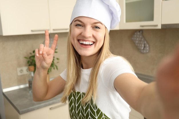 Mujer joven y atractiva chef haciendo selfie en la cocina