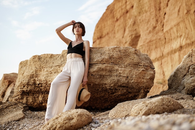 Mujer joven atractiva delgada posando contra rocas de arena