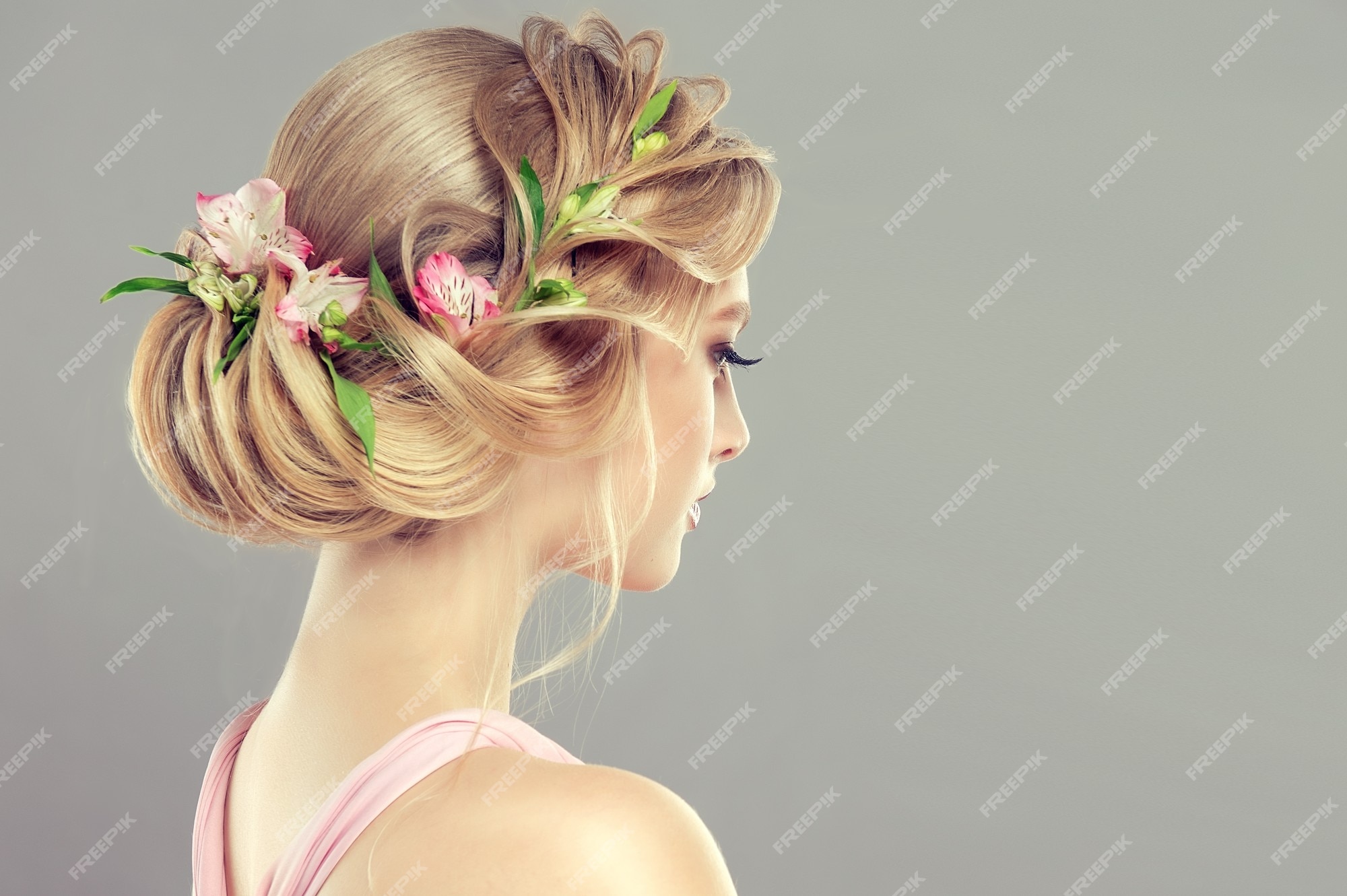 Mujer joven y atractiva está demostrando cabello rubio recogido en un  peinado elegante con flores frescas. arte de la peluquería y coloración del  cabello. vista desde atrás. | Foto Premium